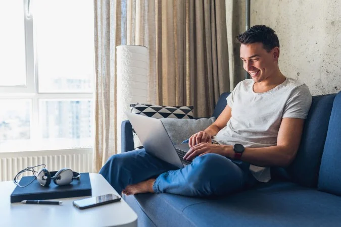 1_young-attractive-man-sitting-sofa-home-working-laptop-online-using-internet-67295363