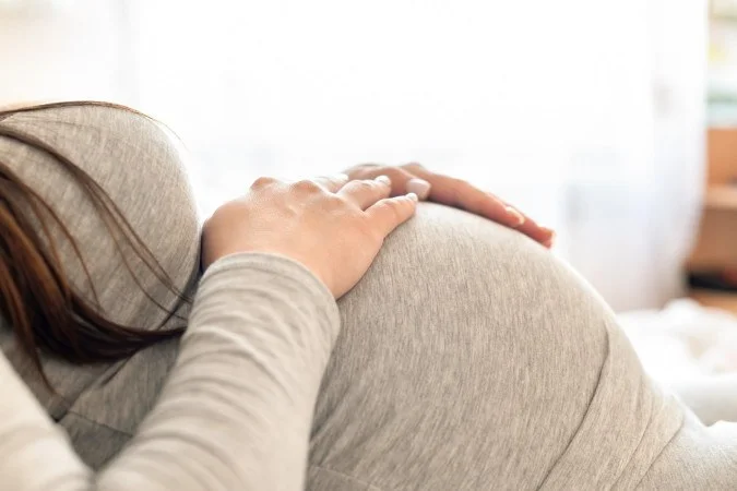 1_pregnant-woman-lying-bed-holding-her-belly-67987263
