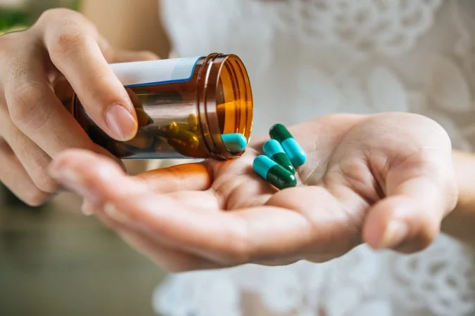 1_woman-s-hand-pours-medicine-pills-out-bottle-68031389
